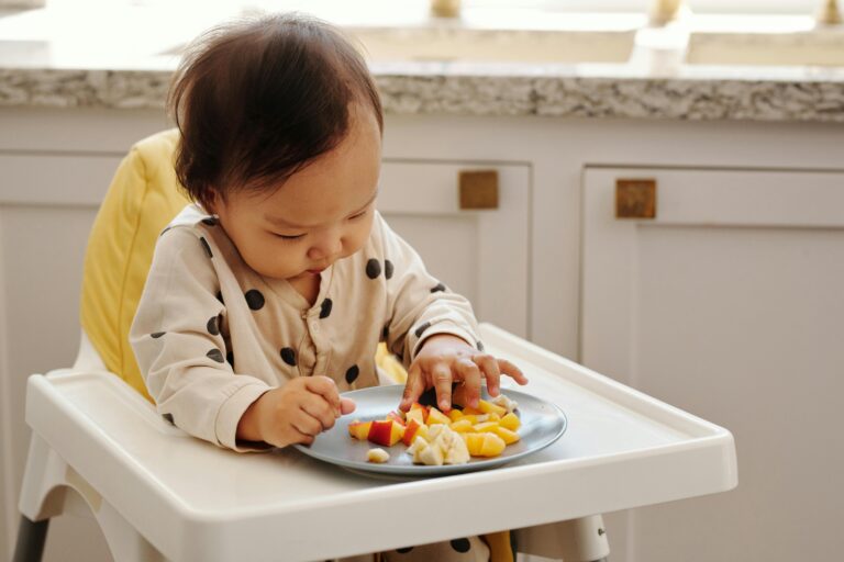 A cute toddler in a polka dot outfit enjoying a healthy fruit snack indoors.